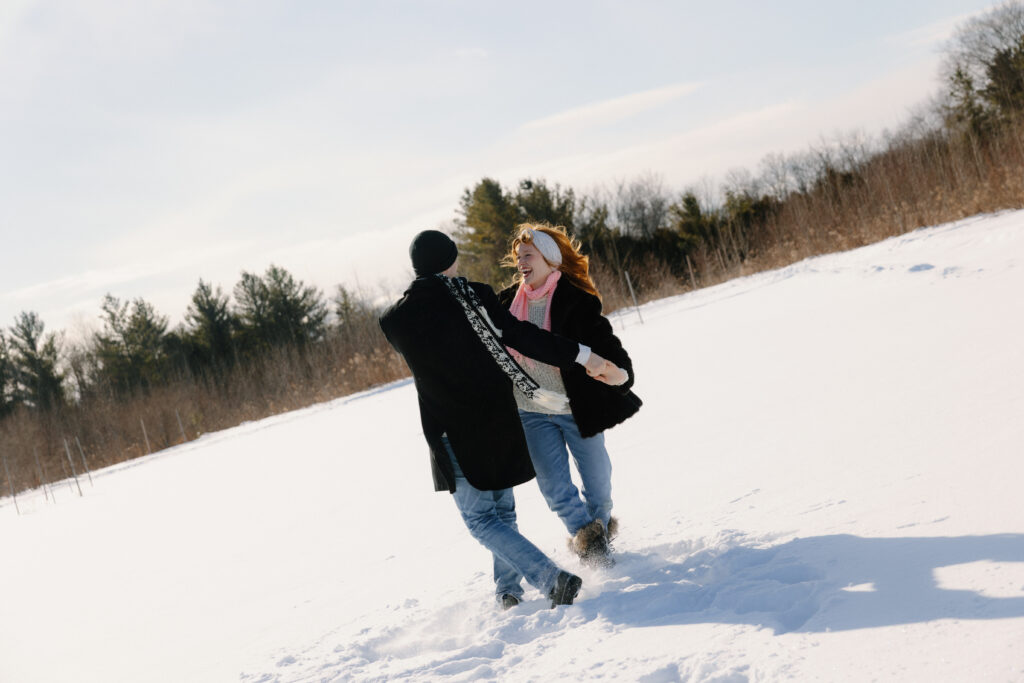 Couple dancing around in the snow in a field