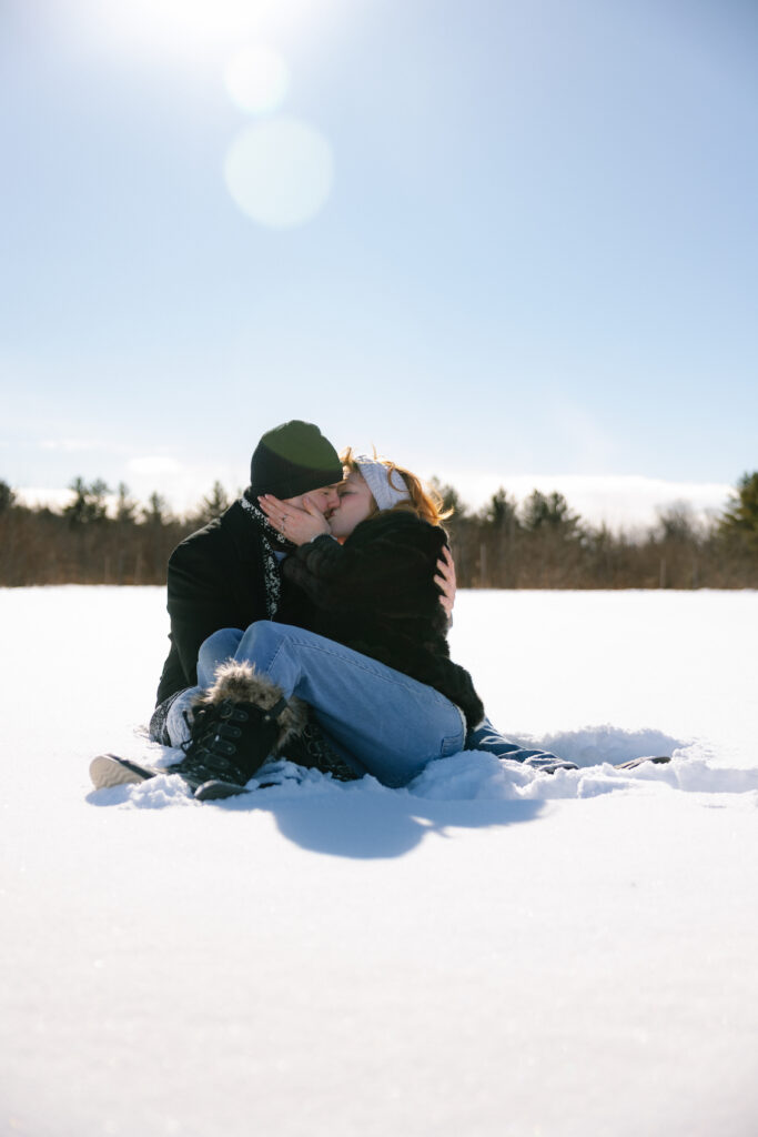 Couple sitting cozy in the snow kissing