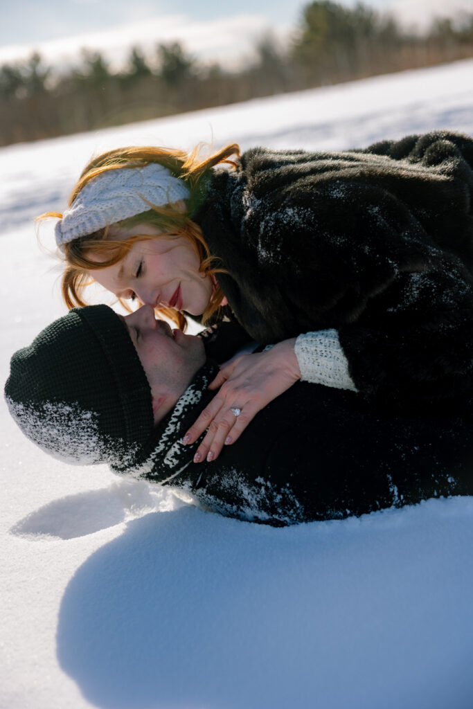 Couple laying in the snow kissingv