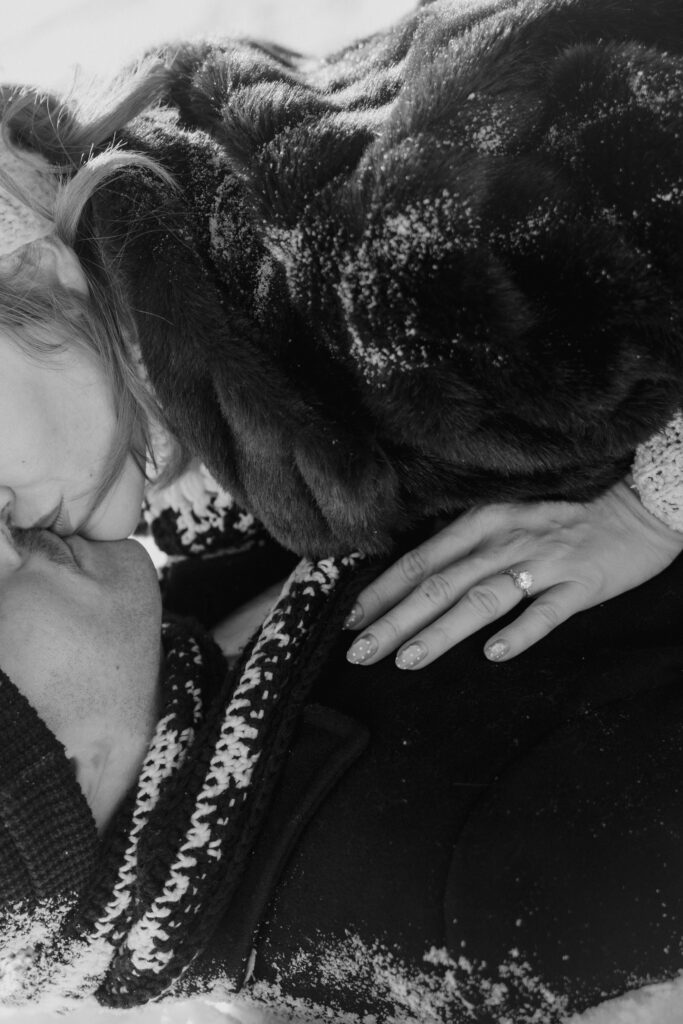 Close up of couple laying in the snow kissing