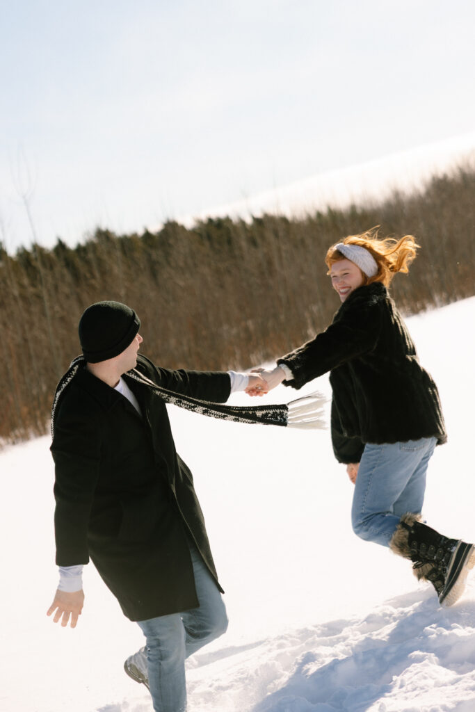 Couple dancing around in the snow in a field