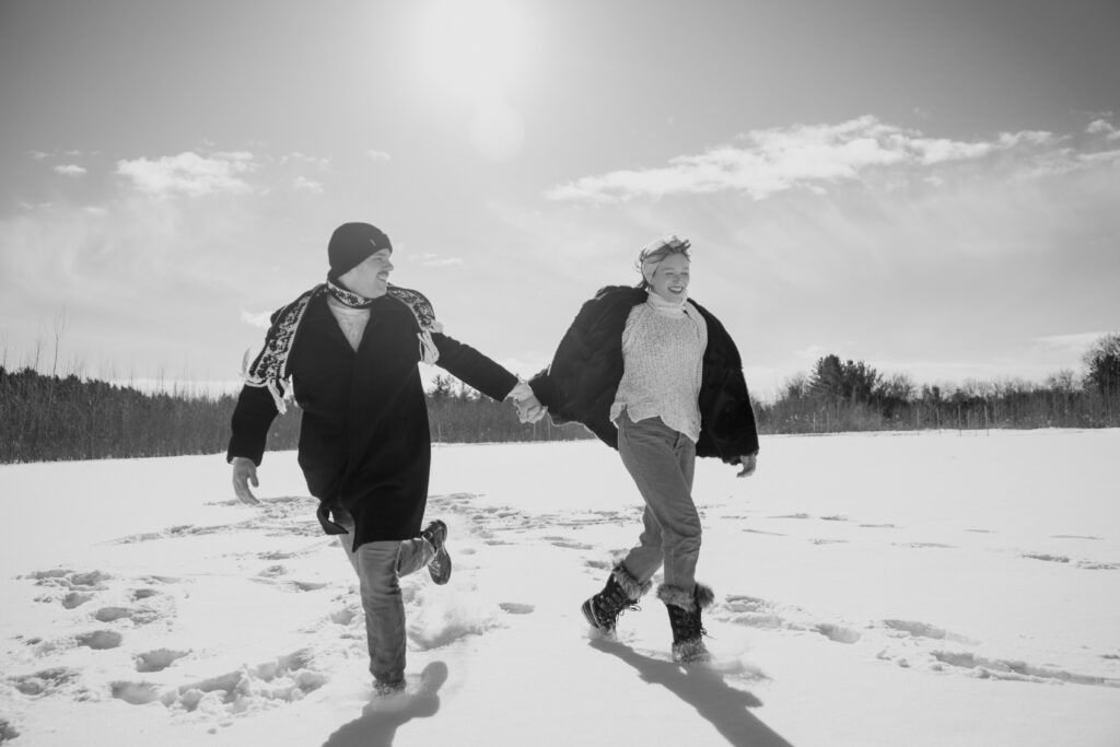 Couple running around in the snow in a field