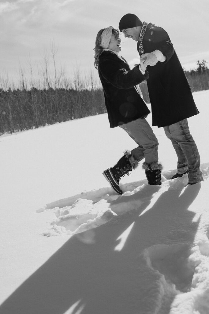 Couple dancing around in the snow in a field