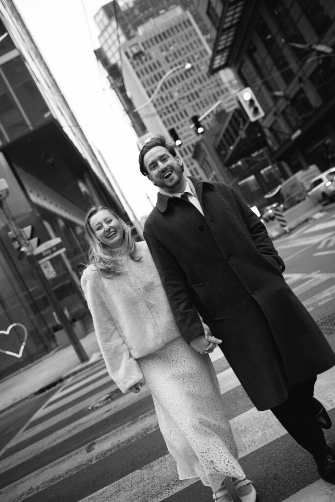 Toronto couple walking across the street downtown laughing