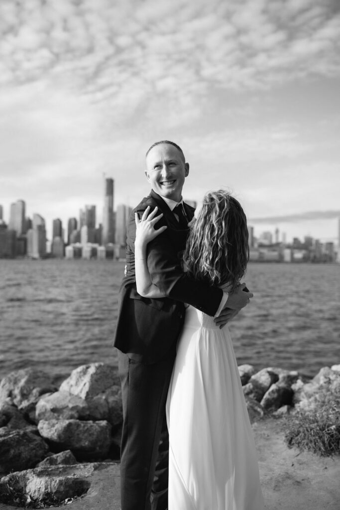 Man smiling while hugging woman with the Toronto skyline behind them
