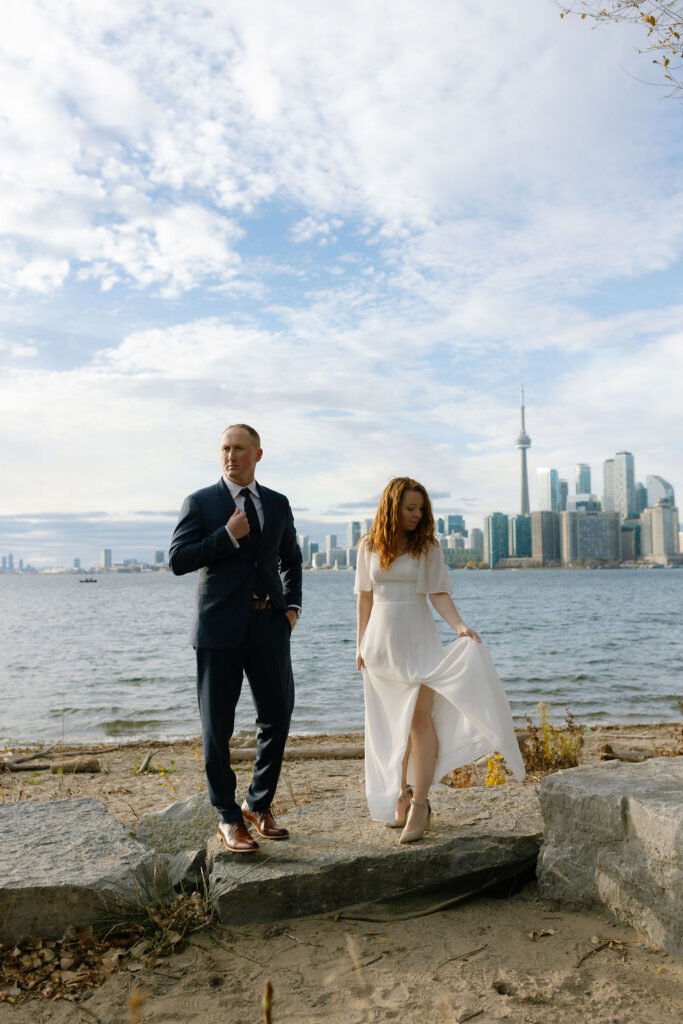 Toronto Island proposal couple fixing their outfits with skyline behind them